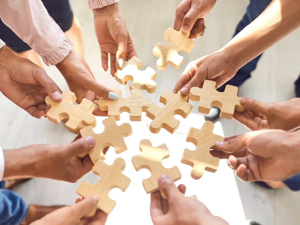 A diverse group of individuals holding wooden puzzle pieces, symbolizing collaboration in non-ADHD partner support groups