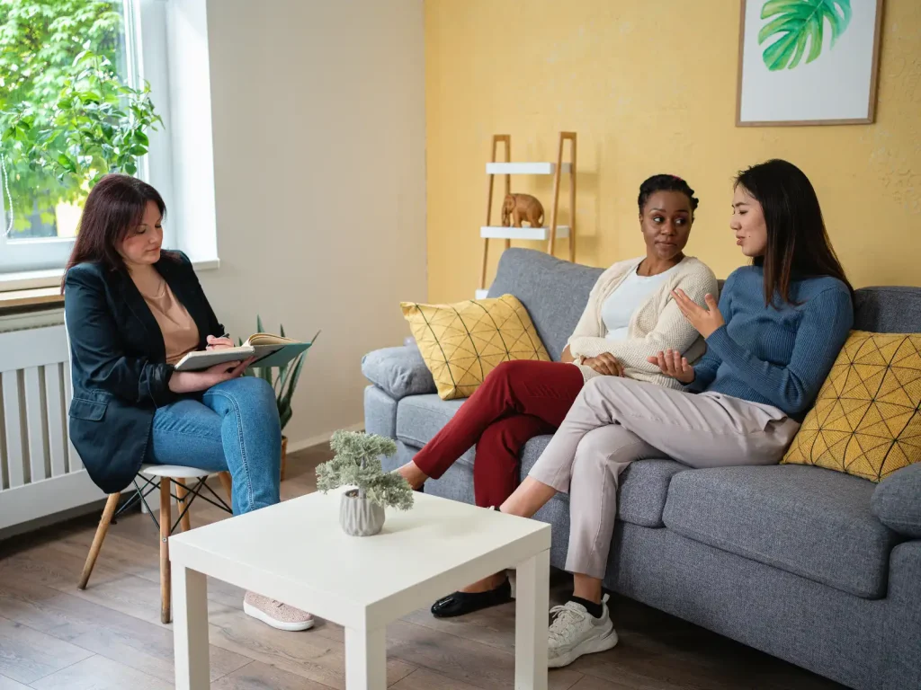 An LGBTQ+ couple engaged in a therapy session with a professional therapist in a warm, inviting space