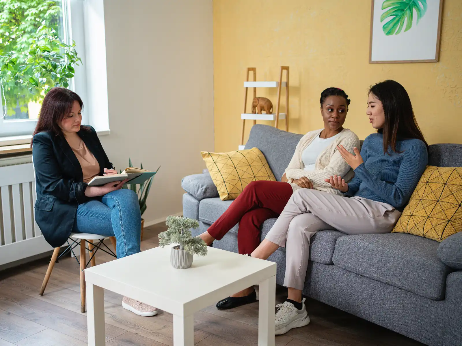 An LGBTQ+ couple engaged in a therapy session with a professional therapist in a warm, inviting space. LGBTQ+ couples therapy provides a supportive environment to strengthen relationships and improve communication.