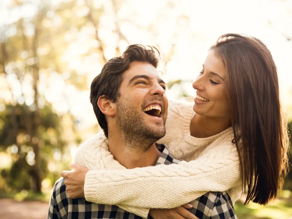 A joyful couple shares a playful piggyback ride outdoors, reflecting the warmth, trust, and connection nurtured through couples counseling in Los Angeles.