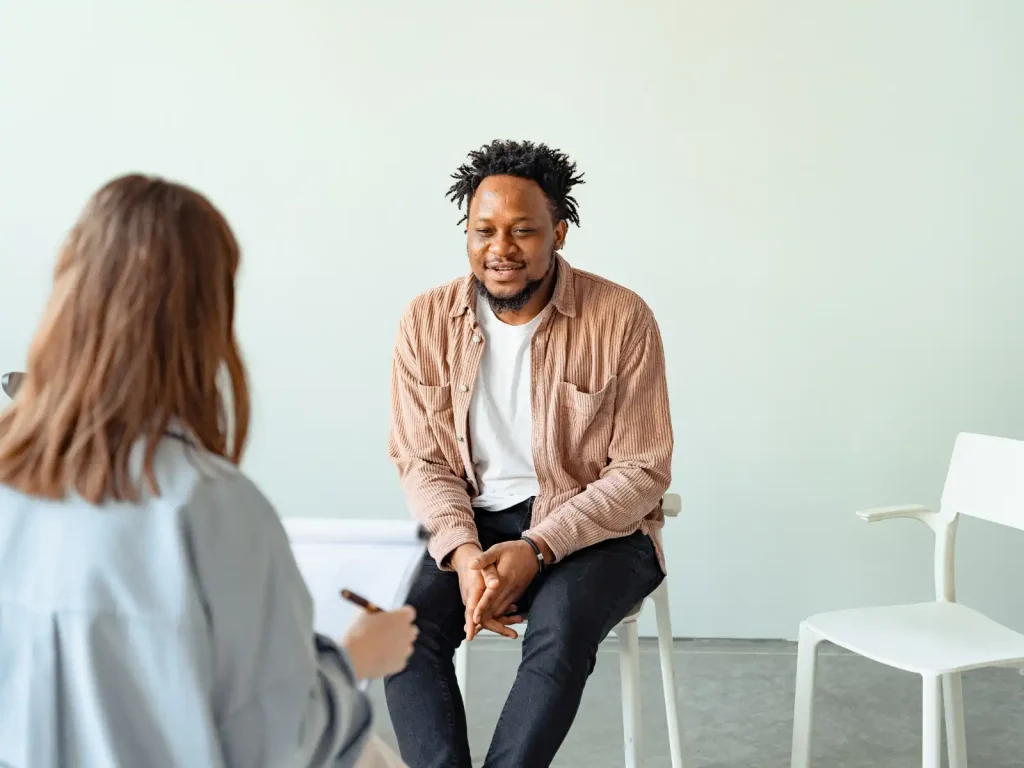 A man sits in a therapy session, engaging in conversation with a professional in a calm, minimalist setting, representing neuropsychological testing and mental health support in Los Angeles.