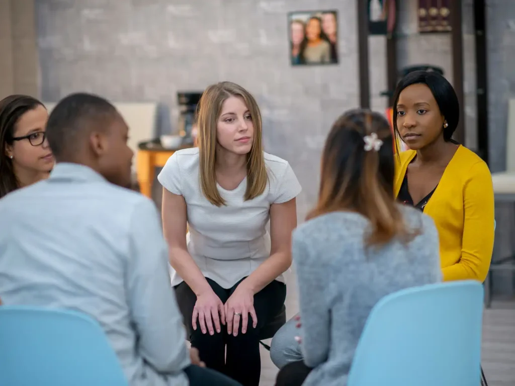 A small group of individuals sitting in a circle, engaged in an empathetic and attentive discussion — a support group for non-ADHD partners