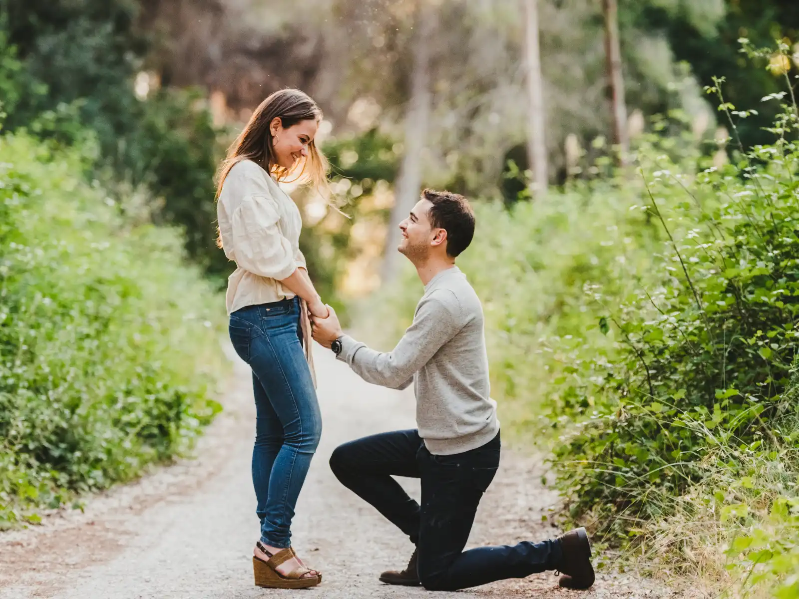 A man proposes to his partner on a scenic wooded path, symbolizing a strong, committed relationship. Pre-marital therapy in Los Angeles helps couples build a solid foundation before marriage.