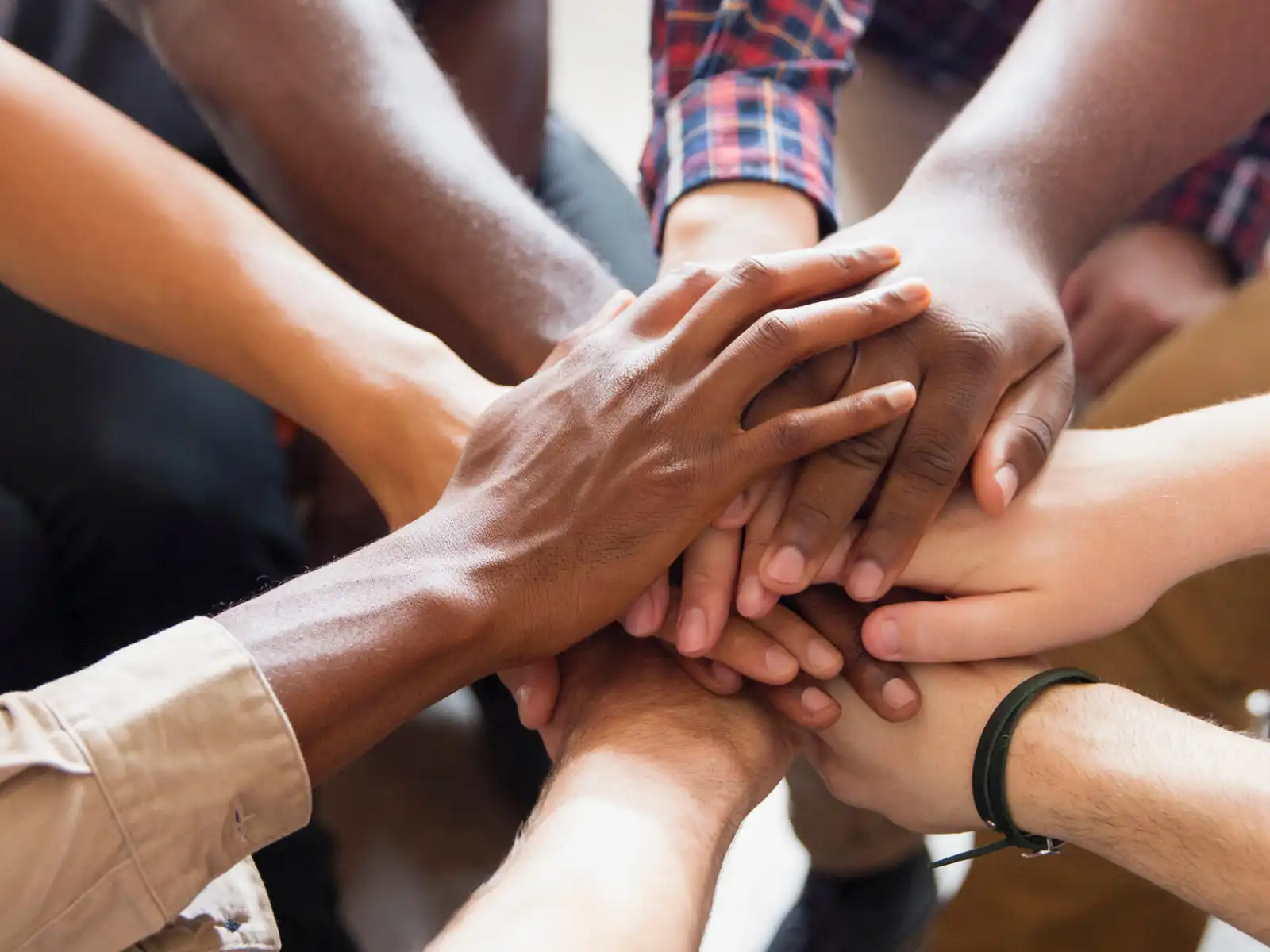 A diverse group of individuals places their hands together in unity, symbolizing trust, support, and the strength of therapy support groups in Los Angeles.