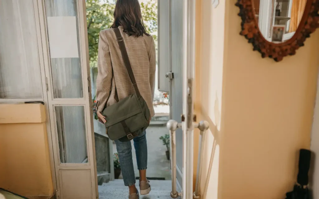 Commitment-couples-therapy A woman leaving her house through the front door carrying a bag symbolizing leaving a relationship due to ineffective couples therapy