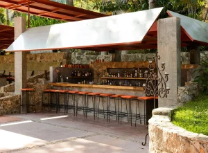 The bar area at Verana, Mexico, an open air setting with rustic stone touches and bar stools. The perfect place for couples to unwind during their retreat.
