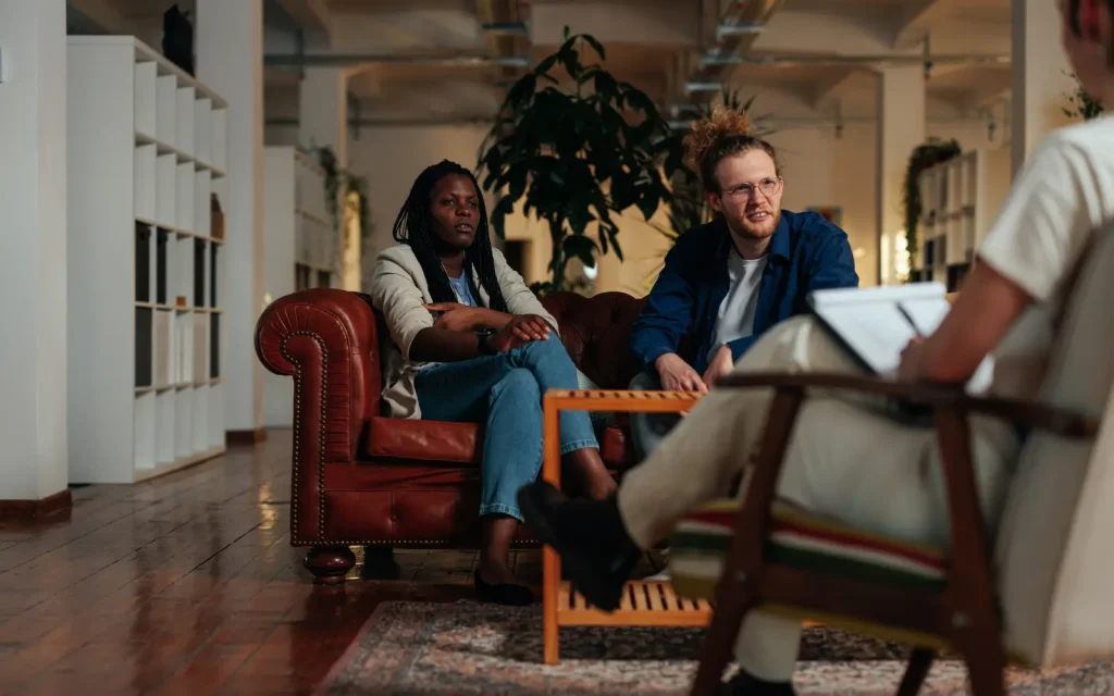 Couples-therapy An interracial couple in a couple's therapy session sitting on a leather couch