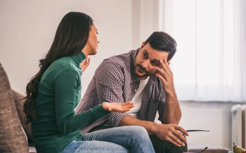 Interracial-couple-discussing-couples-therapy An interracial couple sitting on a couch discussing going to couples therapy