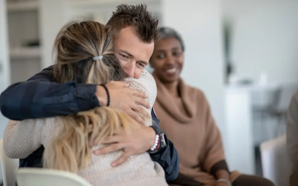 Reflective-couple-in-EFT-therapy A couple hugging in front of their therapist when graduating EFT therapy and reflecting on their past sessions and journey