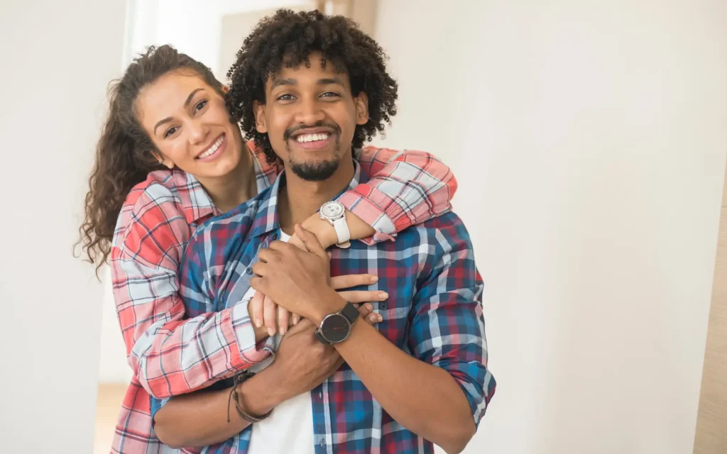 An interracial couple smiling at the camera after attending therapy from a culturally grounded therapist
