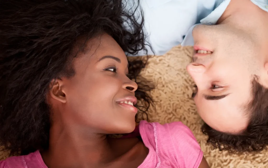 A black woman and white man looking into each other's eyes and smiling, representing the positive benefits of interracial couples therapy