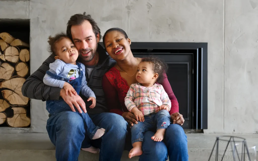 Happy-mixed-race-family-after-couples-therapy A mixed race couple with two young children, smiling at the camera