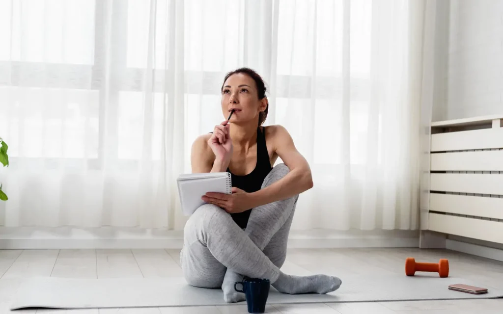 A woman sitting on the floor with a notepad, representing personal growth and insight that is uncovered during couples therapy