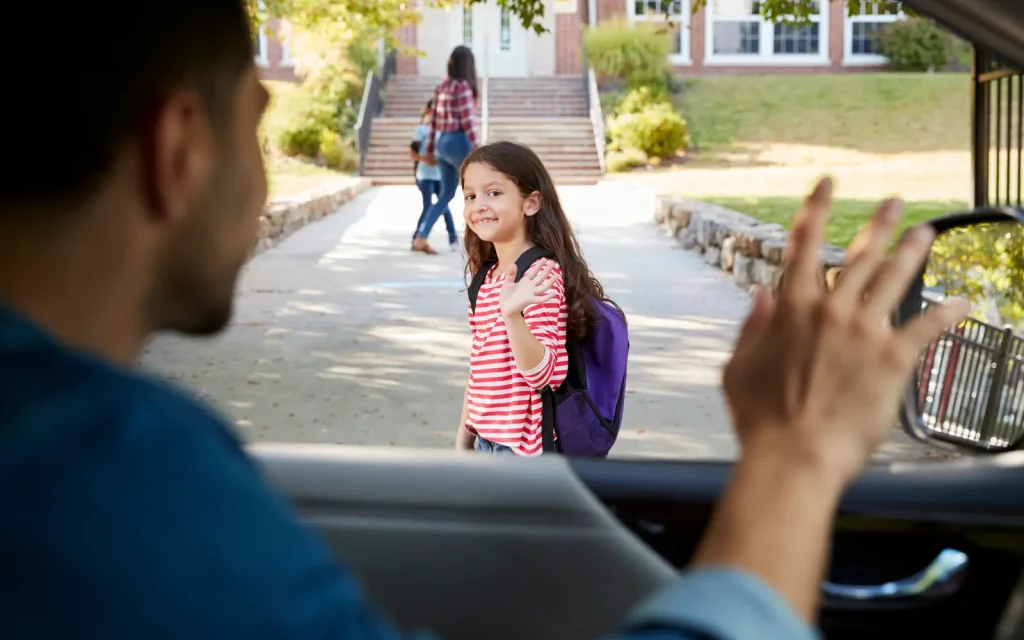 Separated-parent-counseling A man waving goodbye to his daughter after dropping her off at his ex-wife's house, representing the positive impact of separated parents going to couples counseling