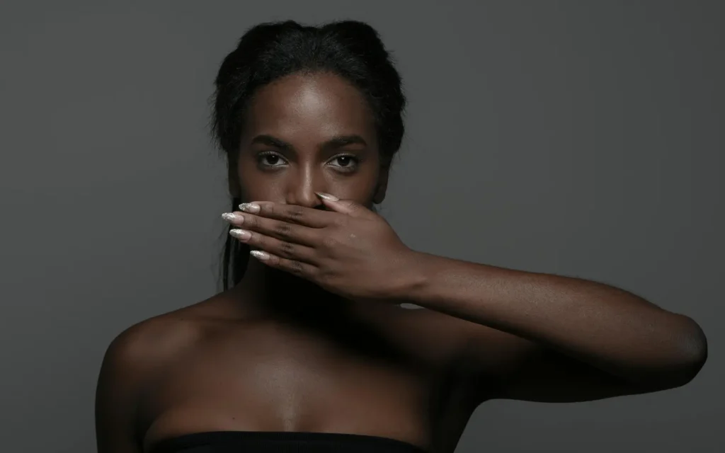 Woman holding her hand over her mouth, representing self-censorship in therapy sessions