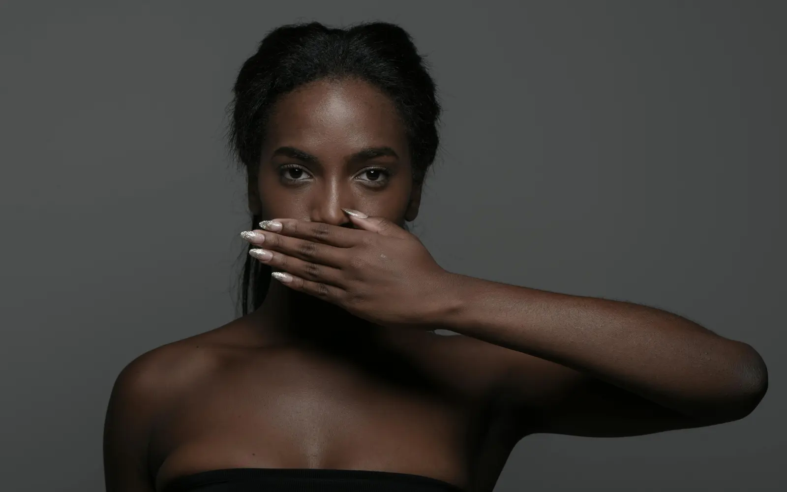 Woman holding her hand over her mouth, representing self-censorship in therapy sessions