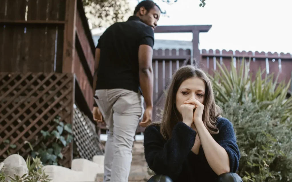A man walking away from a nervous and scared looking woman, representing the lack of safety often present in narcissistic couples