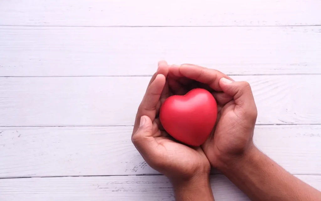 A woman holding a red heart-shaped stone, representing self help tools to manage excessive crying episodes