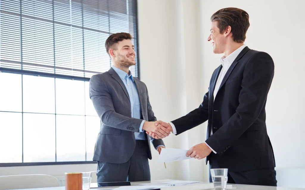 Advocating-for-neurodiverse-workplaces Two men smiling and shaking hands, representing the positive impact of advocating for your neurodiversity in the workplace