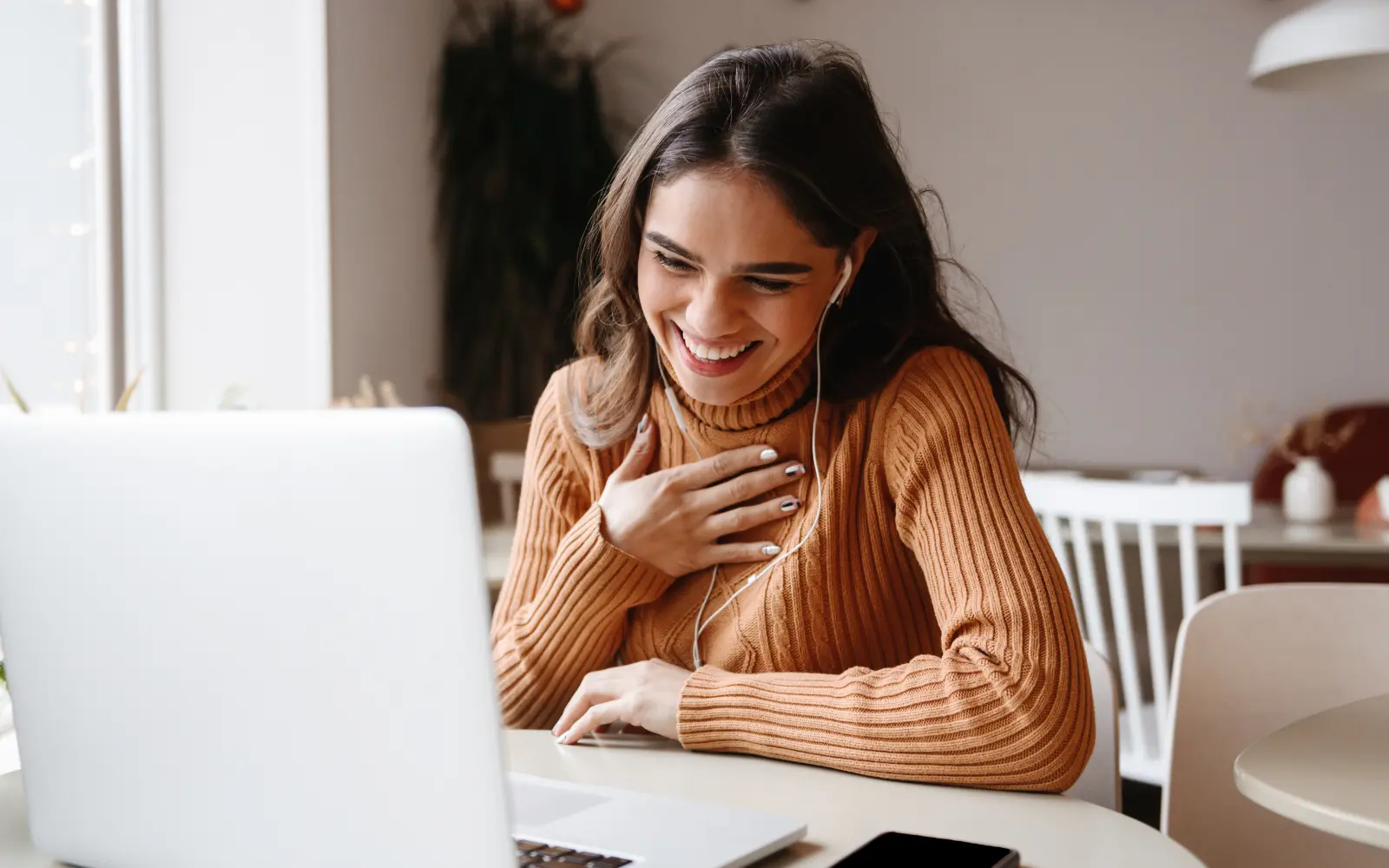 A woman sitting in front of a laptop with her hand over her heart, representing gratitude for online therapy in Los Angeles