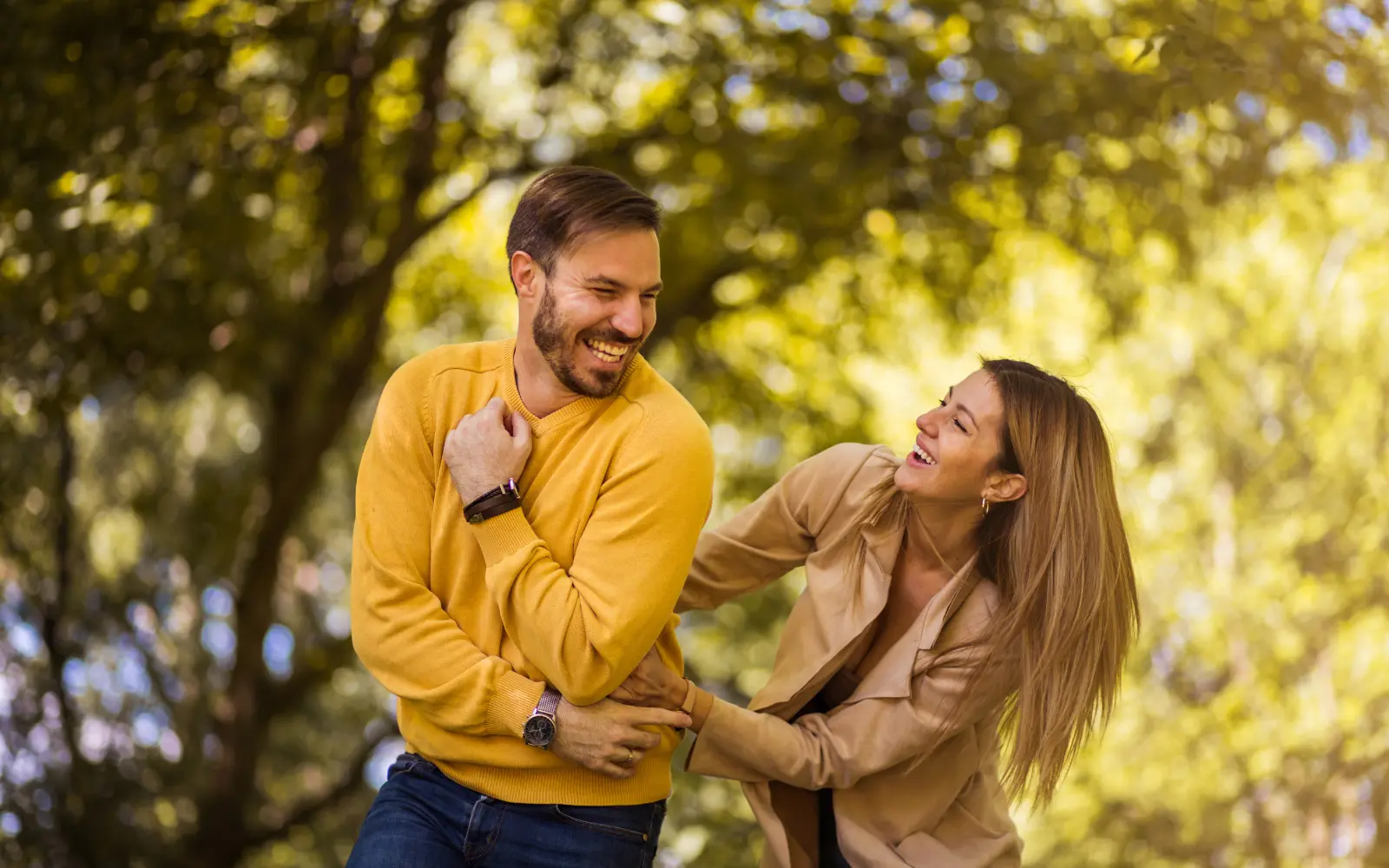 A couple laughing and playfully tickling each other outdoors, representing the reconnection and joy possible after marriage counseling for Los Angeles couples