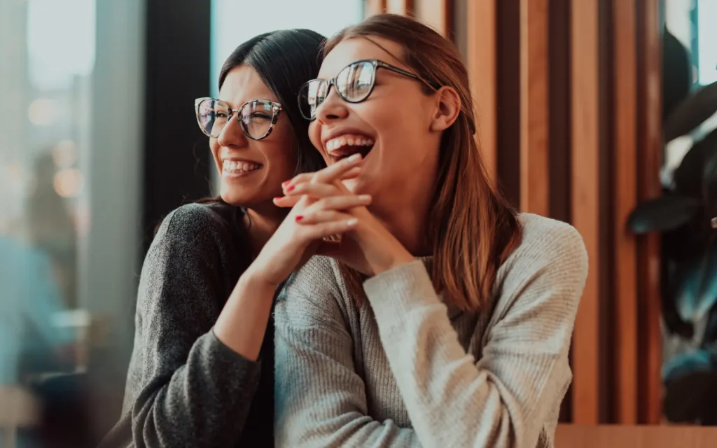 A lesbian couple laughing and holding hands, representing the strengthening of relationships through LA marriage counseling