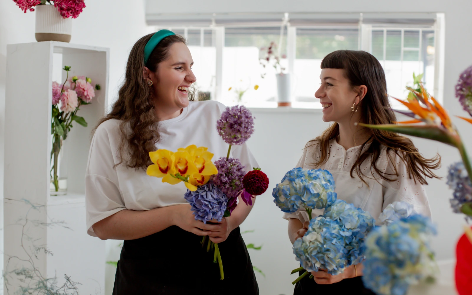 A lesbian neurodivergent couple laughing and holding flowers, representing the impact of therapy for neurodiverse individuals in Los Angeles