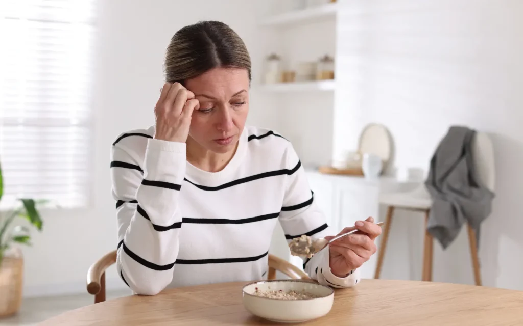 Toxic-relationship-therapy-in-LA A woman sitting at her breakfast table staring at her cereal bowl, representing the impact of toxic relationships and the importance of couples therapy in LA