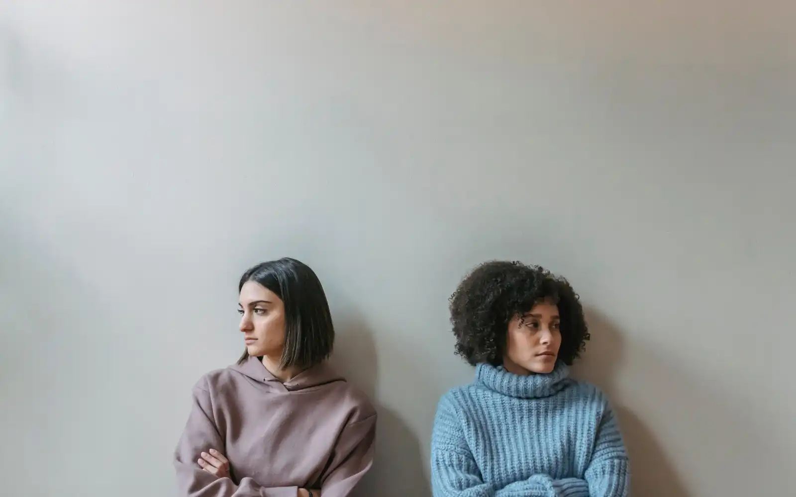 Two women sitting next to each other and facing away from each other, representing the conflict that can arise due to dual relationships in therapy