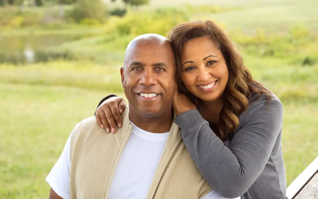 Cultural-factors-in-couples-therapy An interracial couple smiling at the camera, representing cultural differences in couples therapy.
