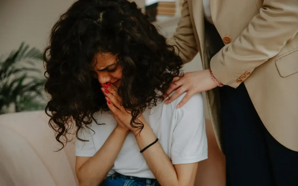 A woman crying and being comforted in a grief counseling session in Los Angeles