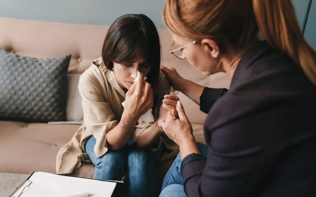 A woman crying on a sofa during psychoanalytic trauma therapy in Los Angeles