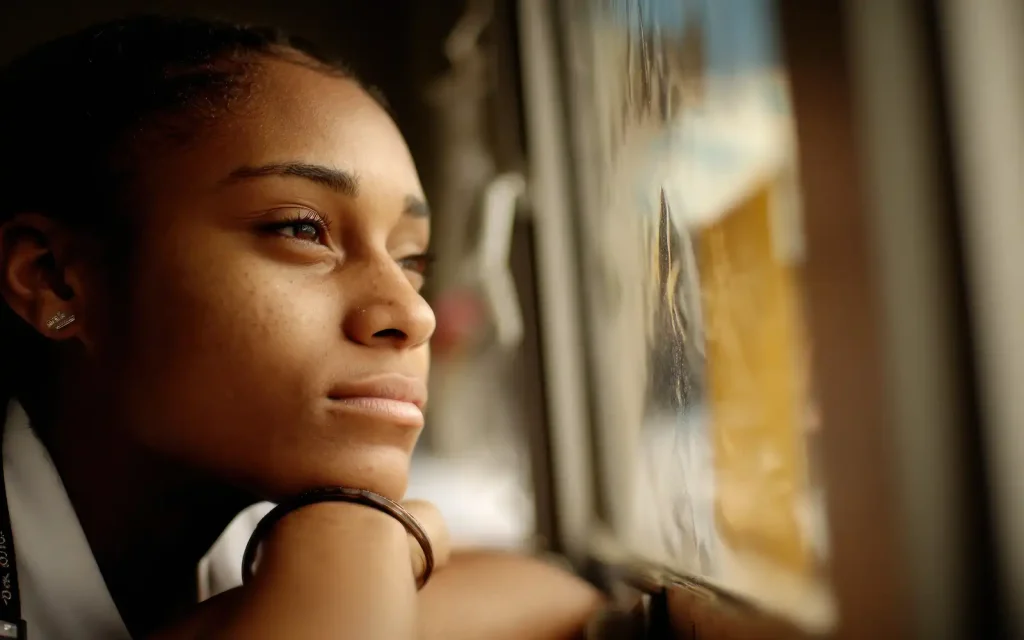 A woman looking pensively out of a window, representing the self-questioning that may lead someone to trauma therapy in LA