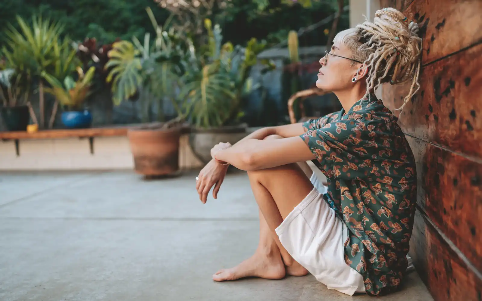 A woman sitting on the floor outside alone, representing the impact of trauma on individuals
