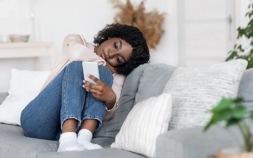 Loneliness-at-Christmas-time A woman sitting on a sofa hugging her legs, representing loneliness at Christmas time
