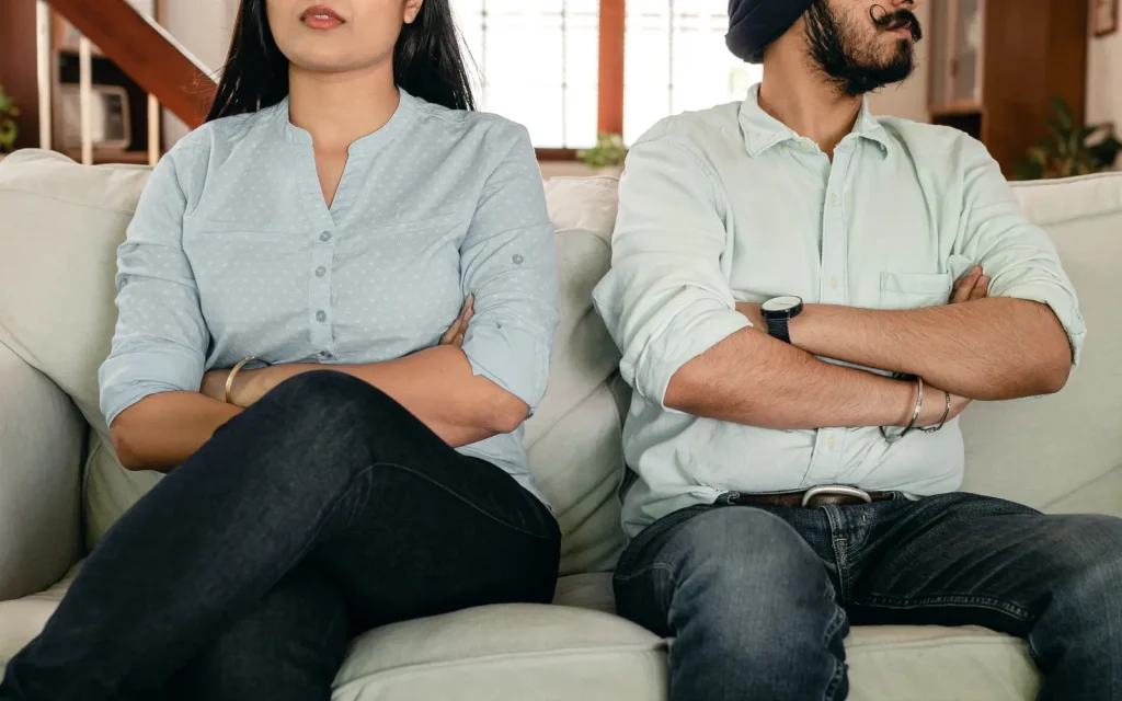 Non-ADHD-partner-overwhelm A couple after an argument sitting on a couch with arms folded, representing the overwhelm the non-ADHD partner can face in neurodiverse relationships