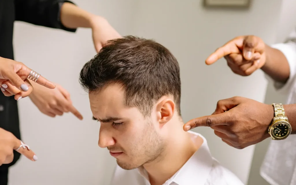 Self-criticism-in-ADHDers A man surrounded by fingers pointing at him, representing the self-criticism many ADHDers feel regularly