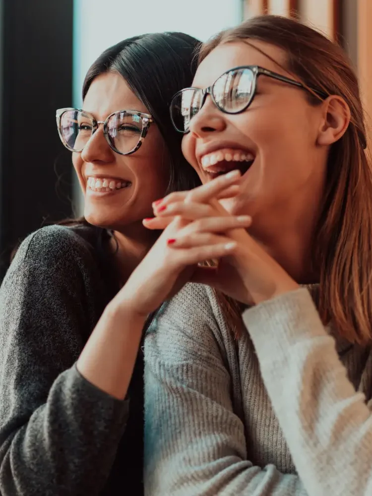 A lesbian couple laughing and holding hands, representing the strengthening of relationships through LA marriage counseling