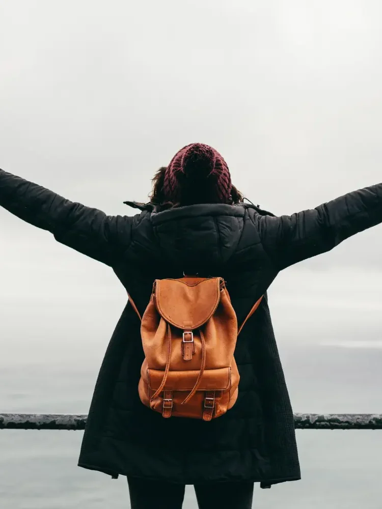 A woman standing on a cliff top with her arms open wide looking out over the sea symbolizing the Freedom you can achieve through individual therapy
