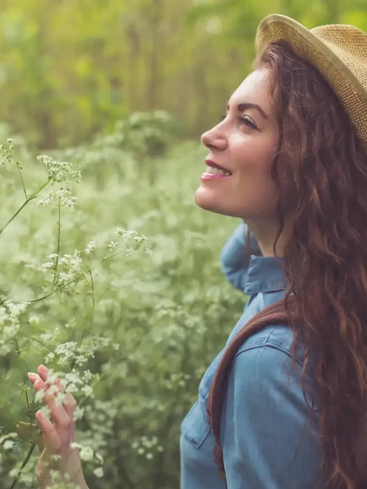 A woman smiling and walking through nature, representing the positive impact of reconnecting with yourself after trauma therapy