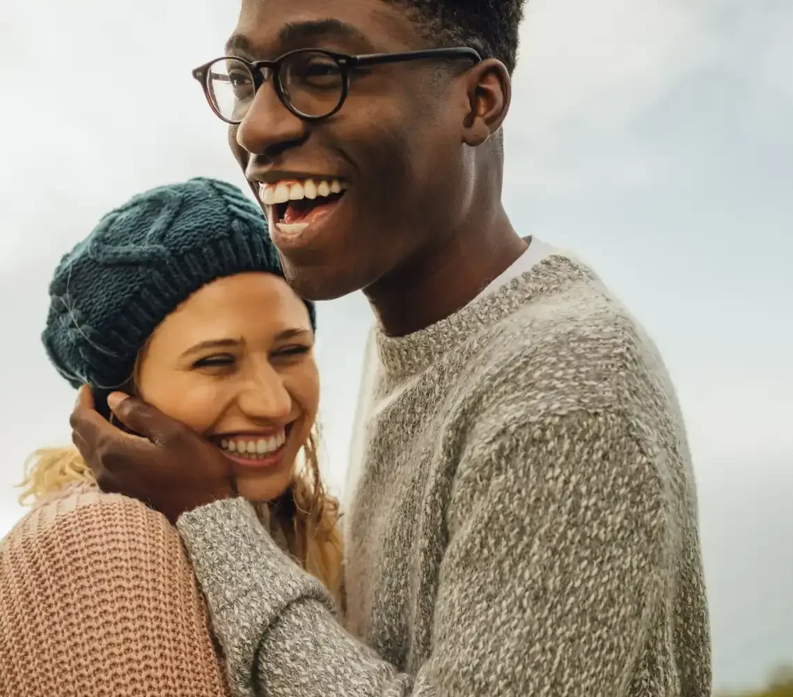 An interracial couple smiling and laughing outdoors, representing the impact of EFT for couples in Los Angeles