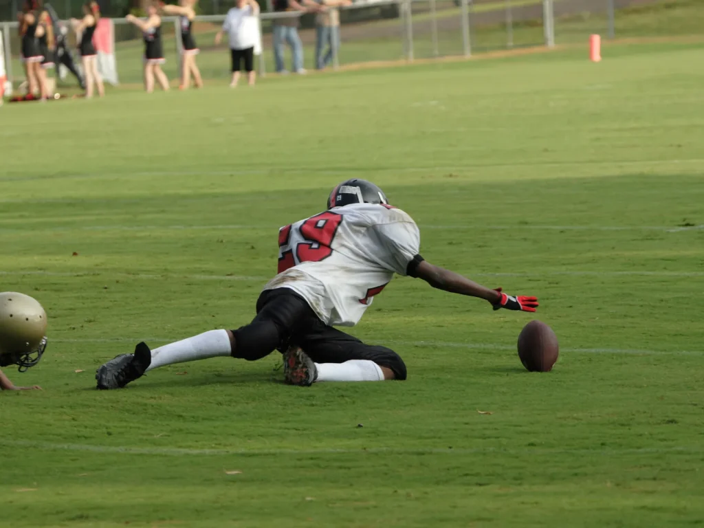 An American Football player fumbling the ball