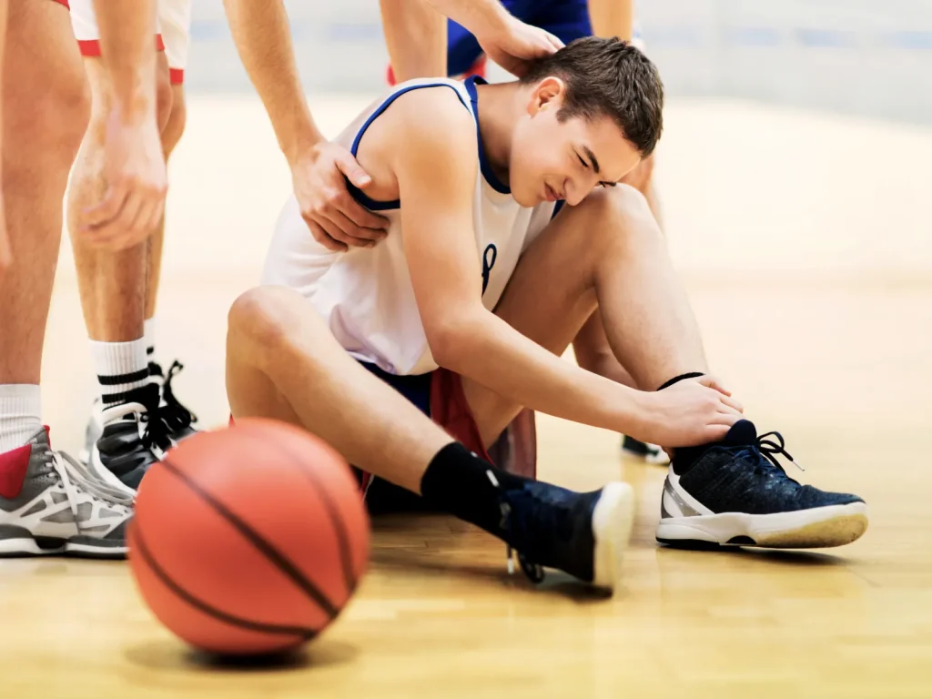 A man on a basketball court suffering an ankle injury