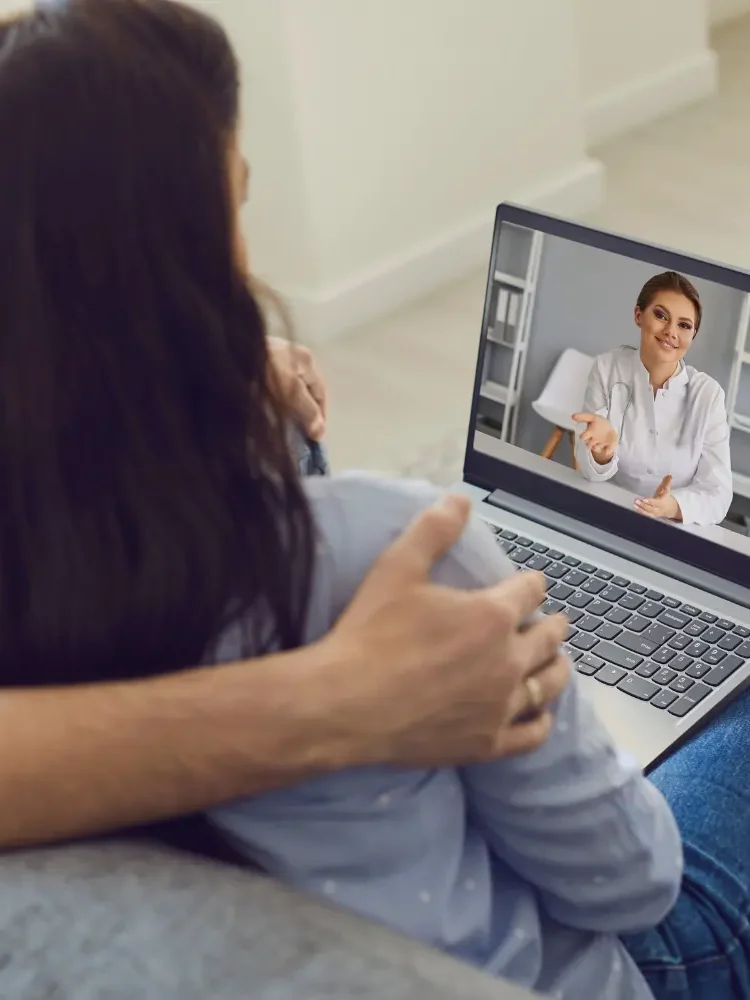 A couple sitting on a sofa with a laptop during an online couples therapy session with one of GGPA's Los Angeles therapists