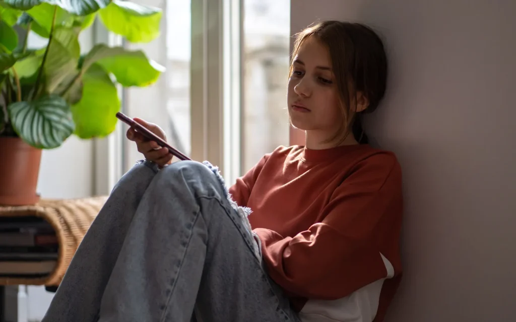 A woman staring vacantly while holding her phone, representing paralysis caused by anxiety